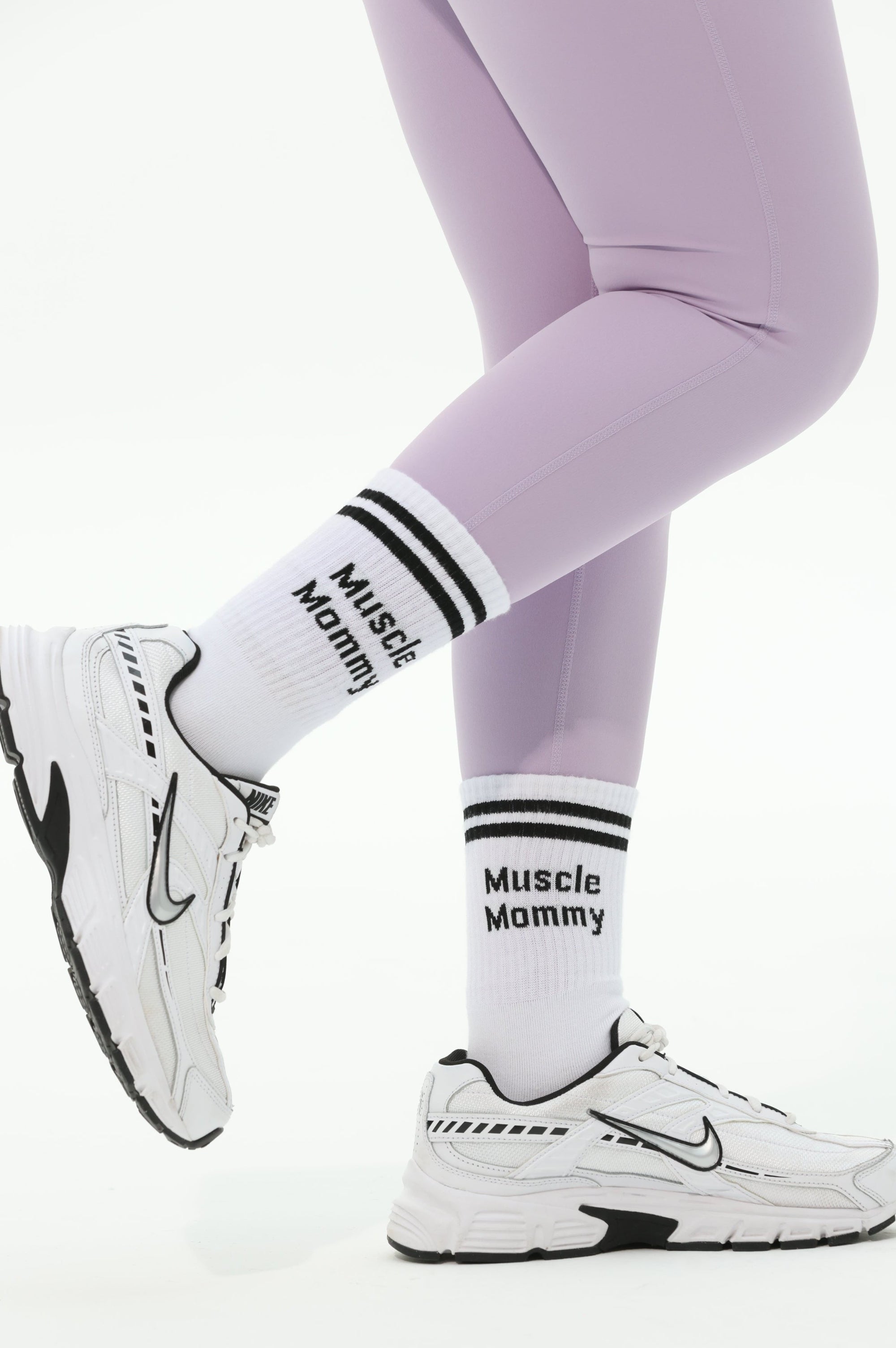 White sneakers and purple leggings with visible branding on a white background