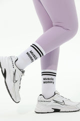 White sneakers and purple leggings with visible branding on a white background