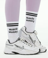 White sneakers with 'Muscle Mommy' socks worn by a person in light purple leggings.