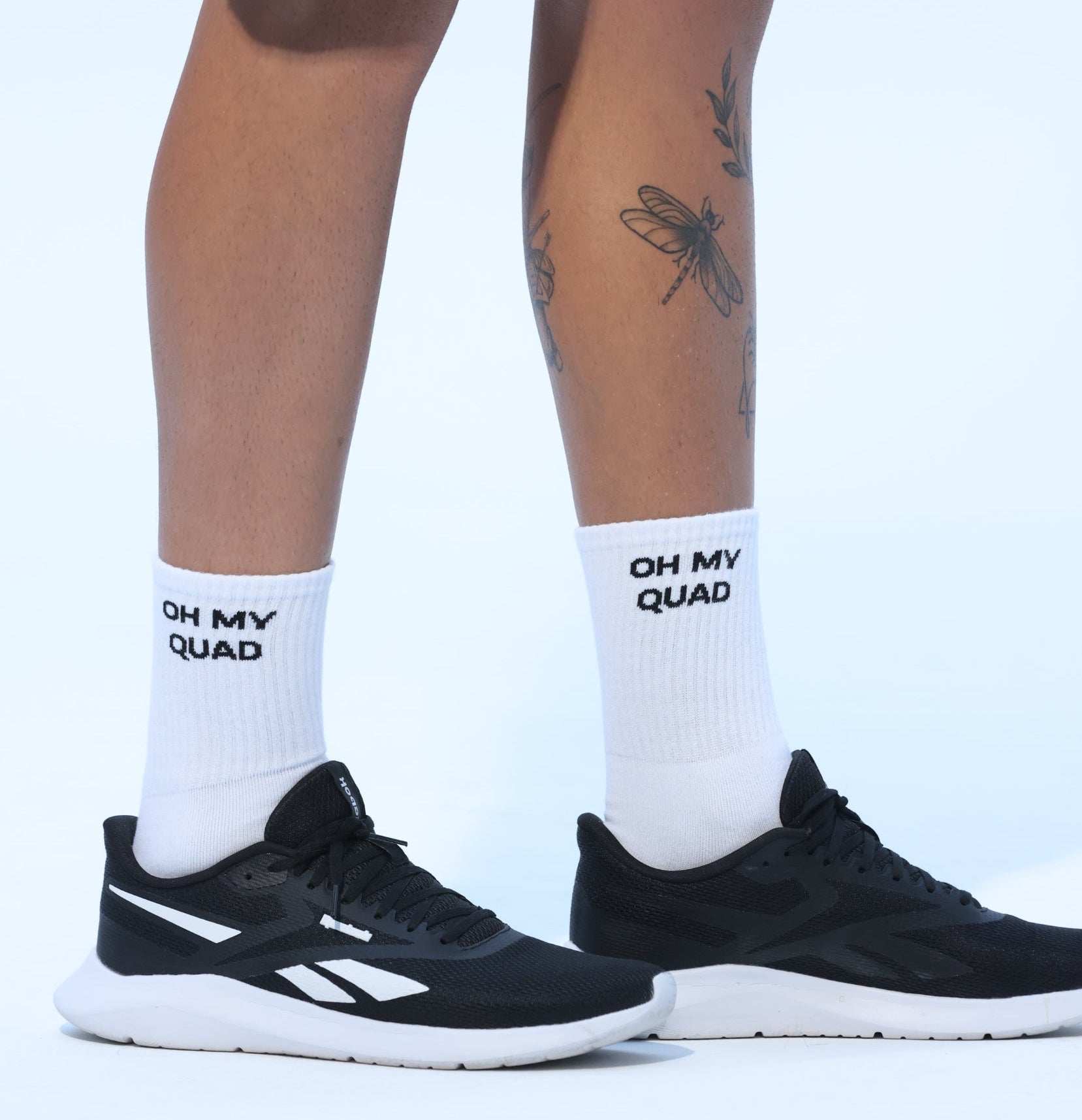 Person wearing black sneakers and white socks with text on a light blue background