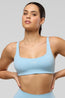 Woman wearing a light blue sports bra and leggings on a gray background