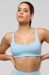 Woman wearing a light blue sports bra and leggings on a gray background