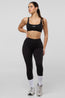 Woman wearing a black sports bra and leggings with a white background