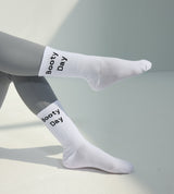 White socks with 'Booty Day' text worn by a person on a light gray background